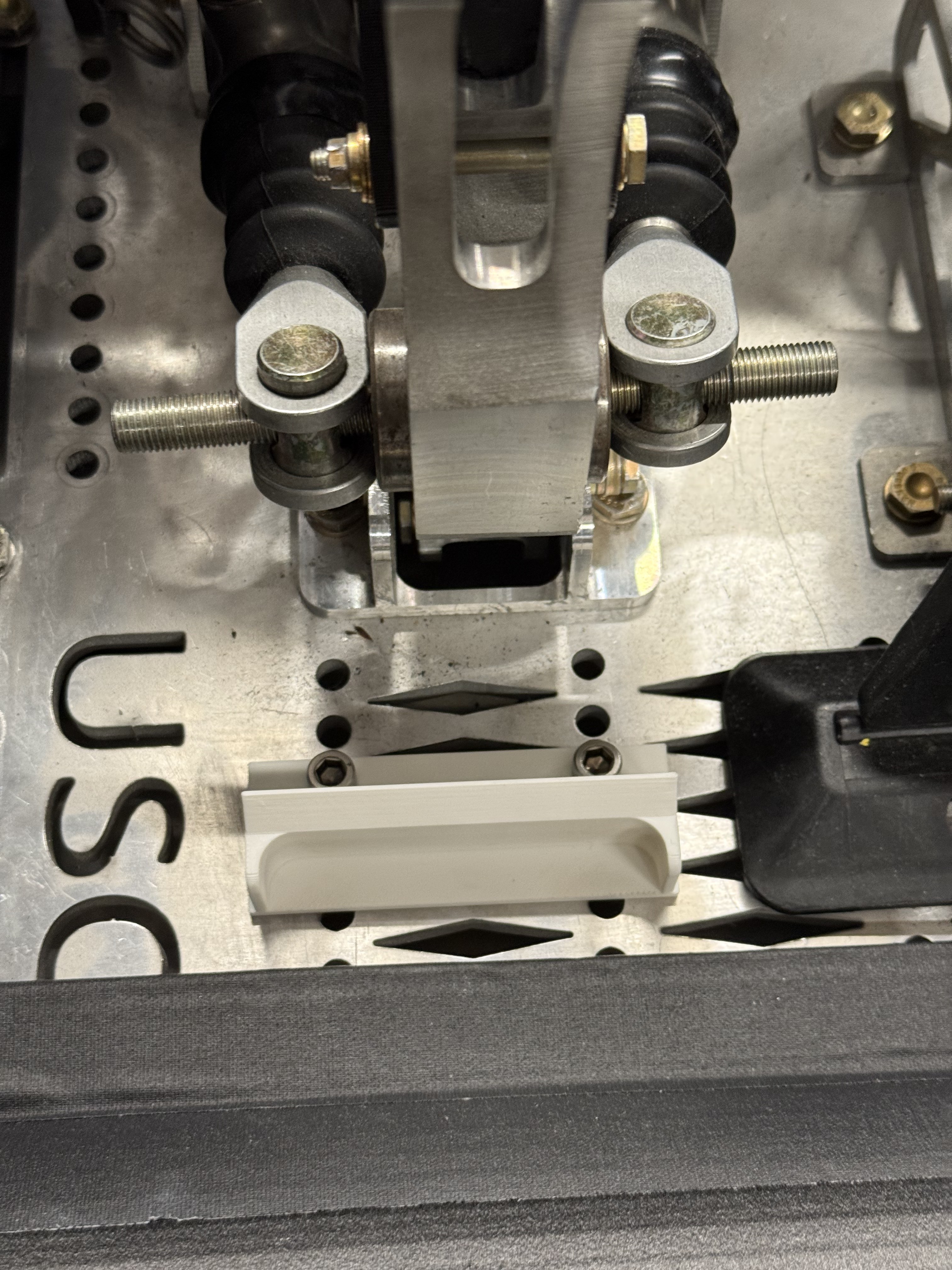 Close-up of brake balance bar and master cylinder hardware on pedal plate